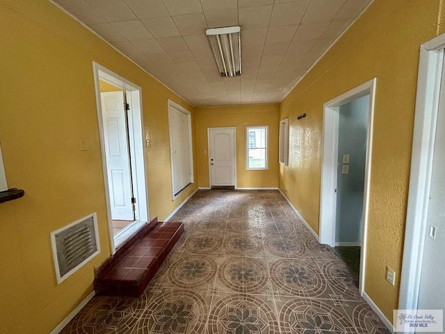hall featuring baseboards and visible vents