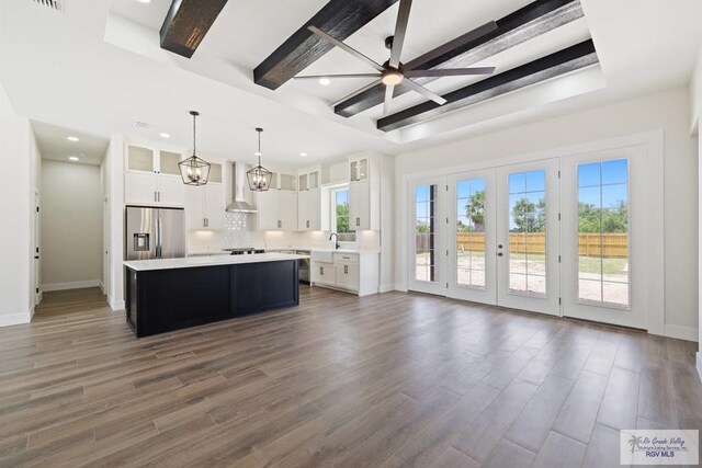 25219 Chelsea Ln, Harlingen, TX 78552 - kitchen featuring stainless steel refrigerator with ice dispenser, wall chimney exhaust hood, light countertops, a center island, and glass insert cabinets