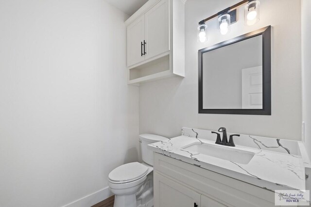 25219 Chelsea Ln, Harlingen, TX 78552 - bathroom with vanity, toilet, baseboards, and wood finished floors