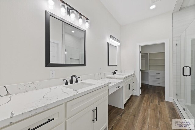 25219 Chelsea Ln, Harlingen, TX 78552 - bathroom featuring a stall shower, two vanities, wood finished floors, and a walk in closet
