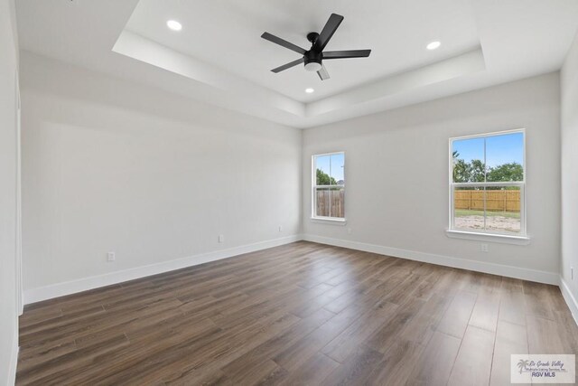25219 Chelsea Ln, Harlingen, TX 78552 - unfurnished room featuring a tray ceiling, dark wood-style flooring, baseboards, recessed lighting, and a ceiling fan
