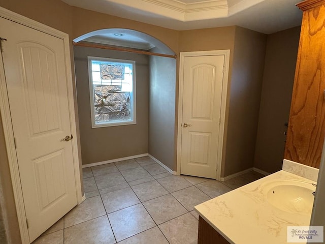 bathroom featuring tile patterned flooring, vanity, a raised ceiling, and ornamental molding