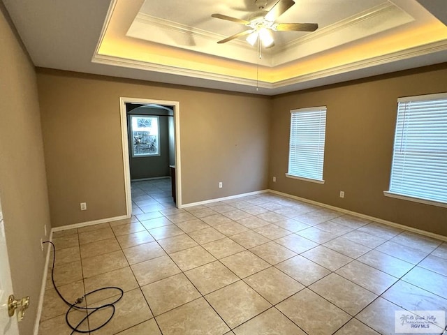 tiled empty room with crown molding, ceiling fan, and a tray ceiling