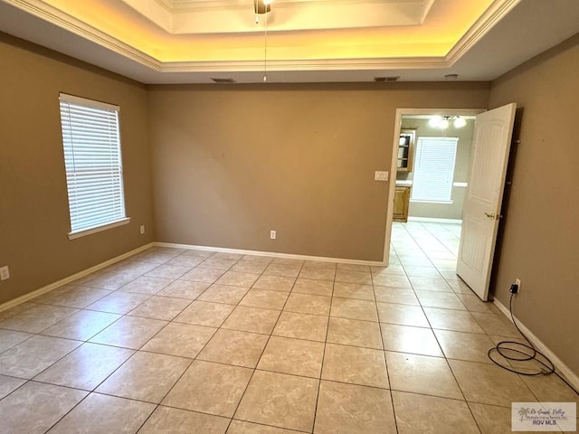 spare room featuring ornamental molding, light tile patterned floors, and a tray ceiling