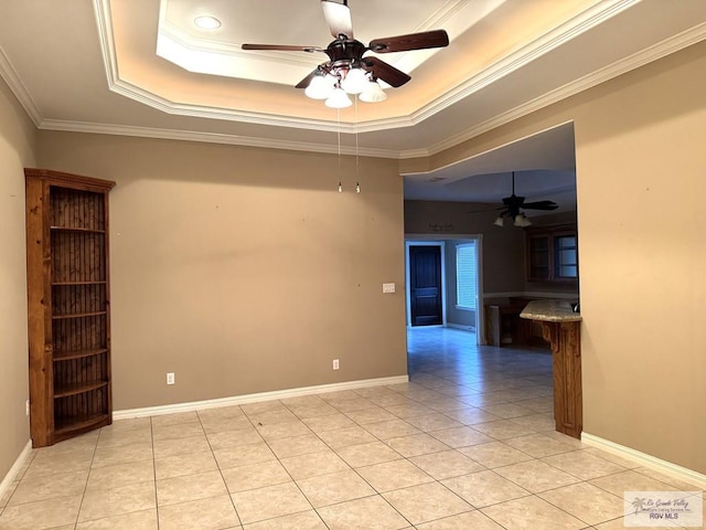 empty room featuring crown molding, ceiling fan, a tray ceiling, and light tile patterned floors