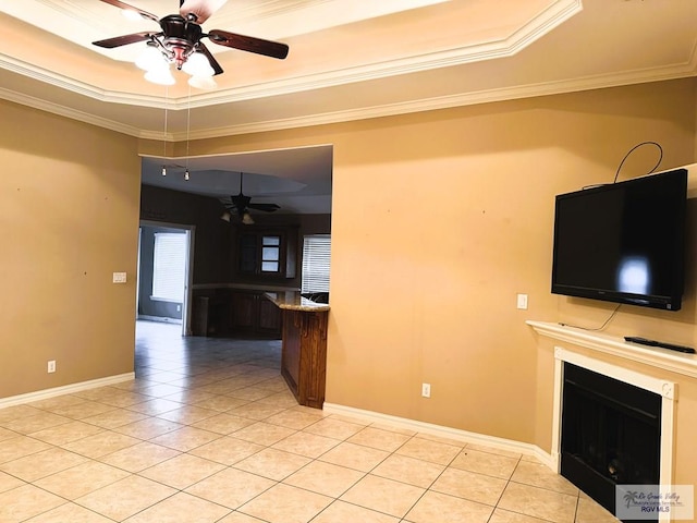 unfurnished living room with a tray ceiling, ornamental molding, ceiling fan, and light tile patterned flooring