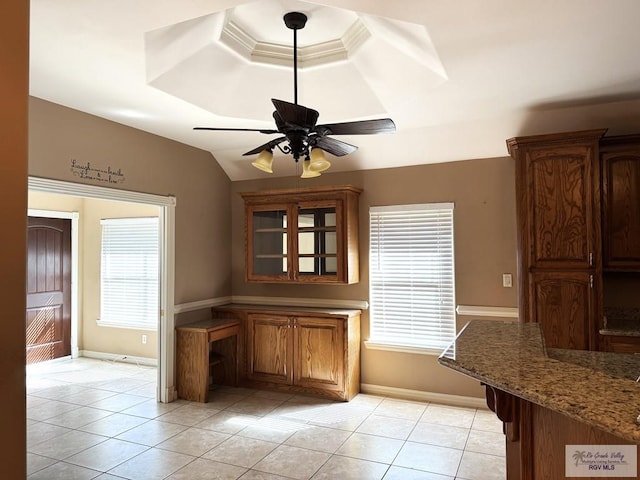 unfurnished dining area with light tile patterned floors, a tray ceiling, vaulted ceiling, and ceiling fan