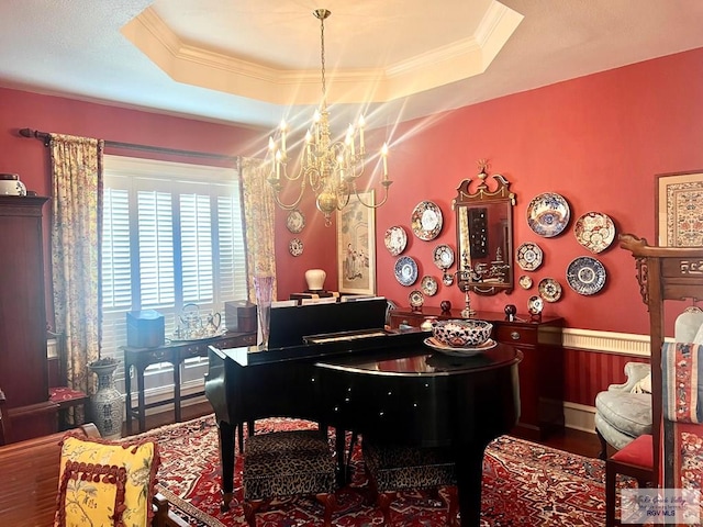 misc room with hardwood / wood-style flooring, an inviting chandelier, ornamental molding, and a tray ceiling