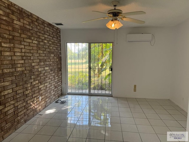 unfurnished room with an AC wall unit, ceiling fan, a textured ceiling, light tile patterned flooring, and brick wall