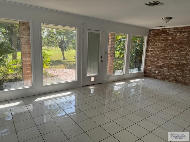 doorway to outside featuring a healthy amount of sunlight, light tile patterned floors, and brick wall