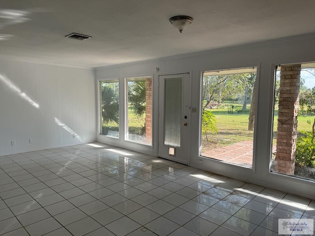 tiled spare room with ornamental molding and a healthy amount of sunlight