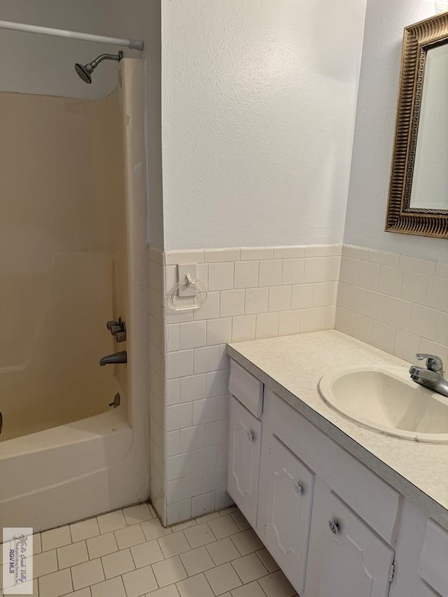 bathroom featuring tile patterned flooring, vanity, tile walls, and washtub / shower combination