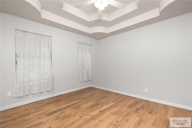 spare room featuring hardwood / wood-style floors, a raised ceiling, and ceiling fan