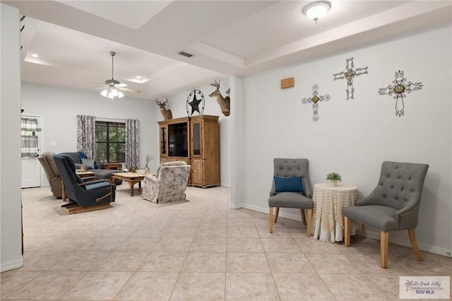 sitting room with ceiling fan, light tile patterned flooring, and a tray ceiling