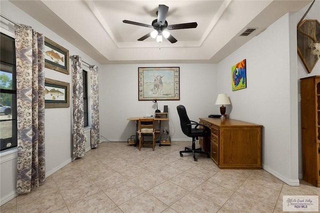 tiled home office featuring a tray ceiling and ceiling fan