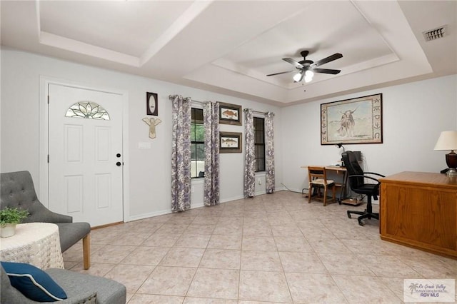 home office with a raised ceiling and ceiling fan