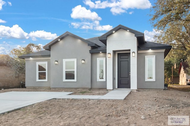 view of front of home featuring roof with shingles and stucco siding