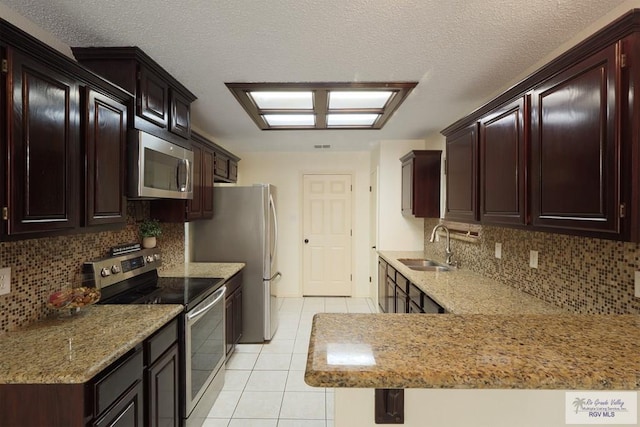 5 Mantua St, Brownsville, TX 78526 - kitchen featuring appliances with stainless steel finishes, light tile patterned flooring, tasteful backsplash, light stone counters, and a textured ceiling