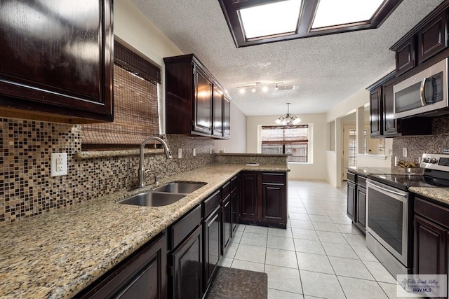 5 Mantua St, Brownsville, TX 78526 - kitchen with stainless steel appliances, a chandelier, light tile patterned floors, backsplash, and rail lighting