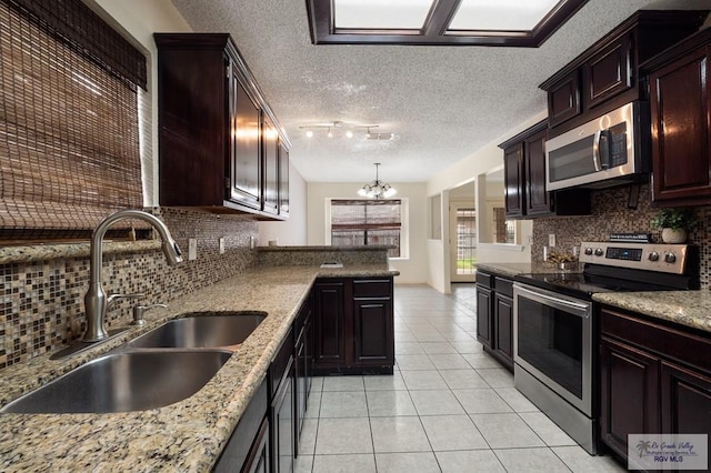 5 Mantua St, Brownsville, TX 78526 - kitchen featuring stainless steel appliances, light tile patterned floors, decorative backsplash, a chandelier, and light stone counters