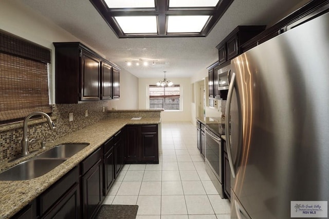 5 Mantua St, Brownsville, TX 78526 - kitchen featuring stainless steel appliances, light tile patterned floors, a chandelier, a peninsula, and tasteful backsplash