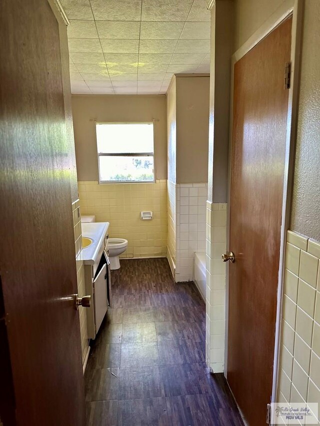 697 W White Ave, Raymondville, TX 78580 - bathroom with tile walls, toilet, vanity, and wainscoting