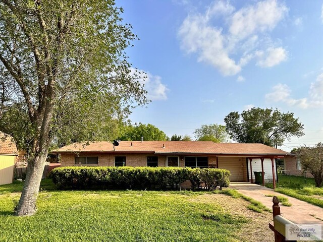 697 W White Ave, Raymondville, TX 78580 - single story home featuring a front yard, driveway, fence, and a carport