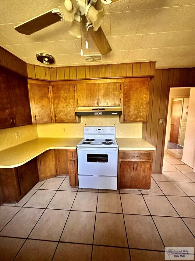 697 W White Ave, Raymondville, TX 78580 - kitchen featuring brown cabinetry, under cabinet range hood, light tile patterned floors, and white electric stove