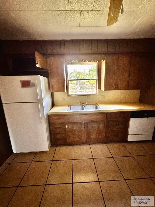 697 W White Ave, Raymondville, TX 78580 - kitchen with light tile patterned floors, a sink, light countertops, white appliances, and brown cabinetry