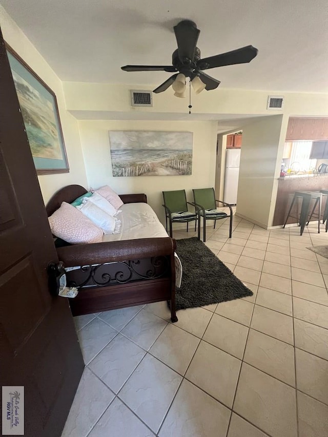 tiled bedroom with white fridge and ceiling fan