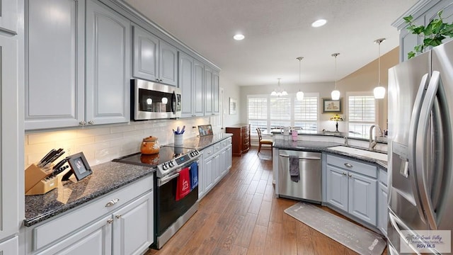 kitchen featuring dark hardwood / wood-style floors, gray cabinets, appliances with stainless steel finishes, decorative light fixtures, and a chandelier