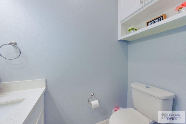 bathroom with toilet, vanity, and baseboards