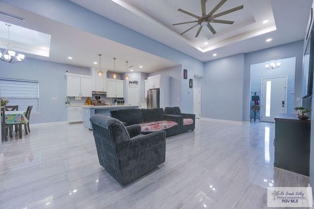 living area with ceiling fan with notable chandelier, baseboards, recessed lighting, and a raised ceiling