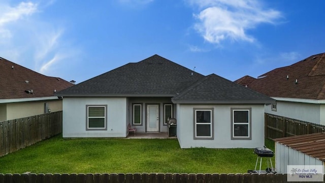 rear view of house with a fenced backyard, a shingled roof, a yard, a patio, and stucco siding