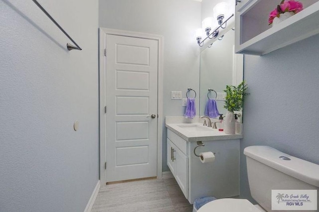 bathroom featuring toilet, vanity, and baseboards