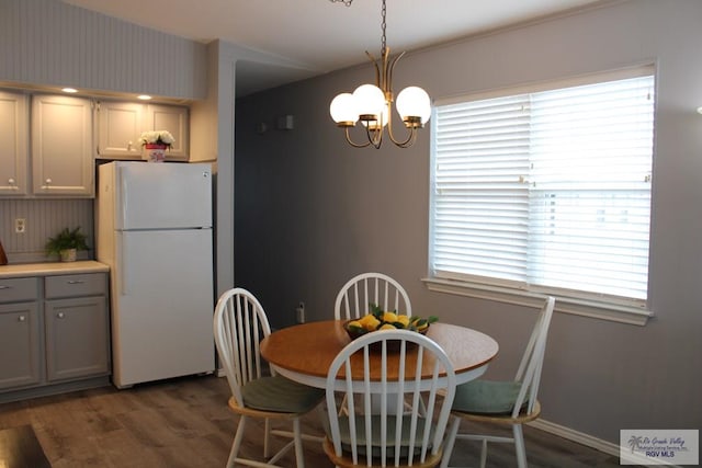 dining space with dark wood-type flooring and a notable chandelier