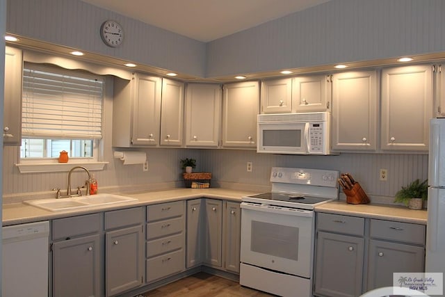 kitchen featuring sink, white appliances, gray cabinetry, and dark wood-type flooring