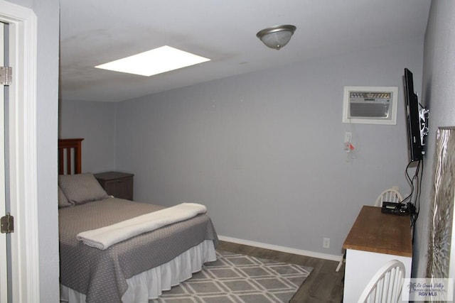 bedroom with a wall mounted AC, a skylight, and dark hardwood / wood-style floors