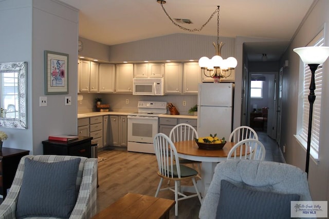 kitchen featuring hanging light fixtures, white appliances, lofted ceiling, a chandelier, and light wood-type flooring