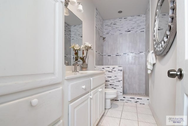 bathroom with tiled shower, tile patterned floors, vanity, and toilet