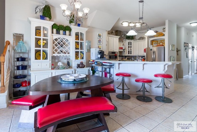 kitchen with white cabinets, light tile patterned floors, stainless steel appliances, and a notable chandelier