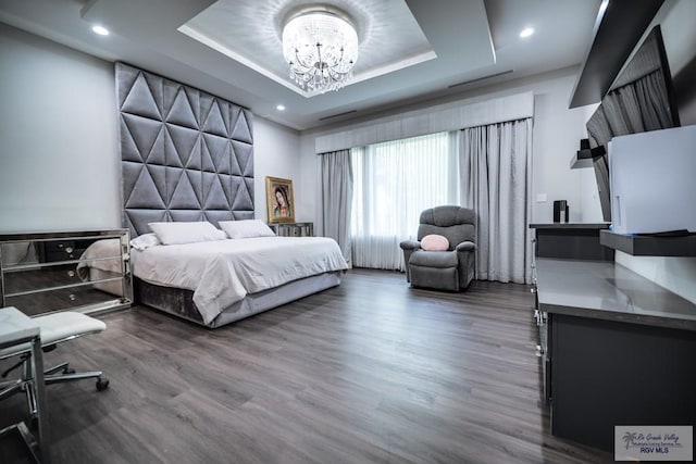 bedroom featuring a raised ceiling, dark hardwood / wood-style floors, and a notable chandelier