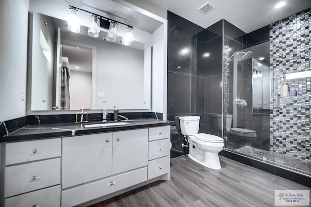 bathroom featuring tasteful backsplash, vanity, a shower with door, hardwood / wood-style floors, and toilet