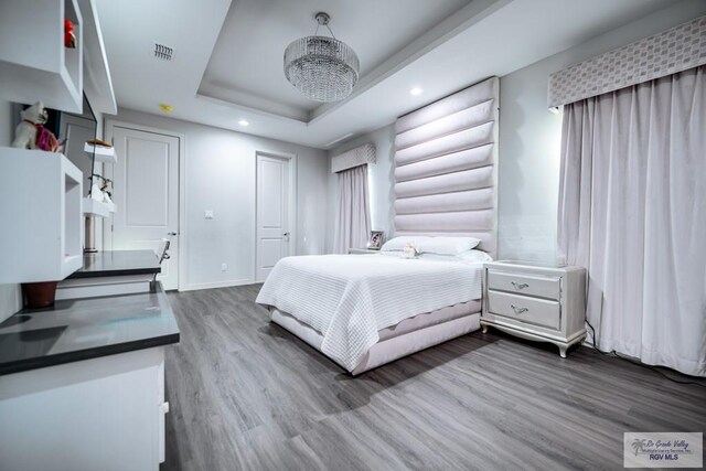 bedroom featuring hardwood / wood-style flooring and a raised ceiling