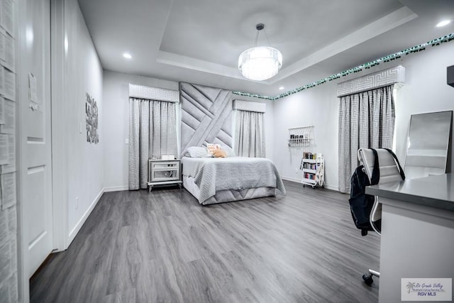 bedroom with wood-type flooring and a tray ceiling