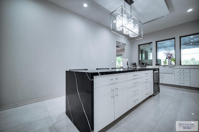 kitchen with decorative light fixtures, a center island, white cabinetry, and a wealth of natural light