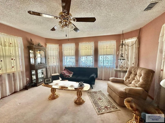 carpeted living room with ceiling fan and a textured ceiling