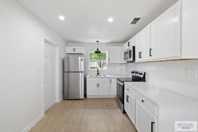 1522 Ball St, Harlingen, TX 78550 - kitchen featuring appliances with stainless steel finishes, light wood finished floors, backsplash, recessed lighting, and white cabinetry