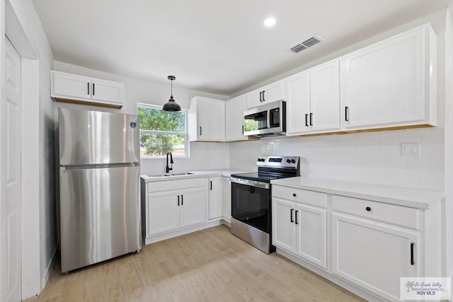 1522 Ball St, Harlingen, TX 78550 - kitchen featuring appliances with stainless steel finishes, light wood-style floors, white cabinetry, tasteful backsplash, and recessed lighting