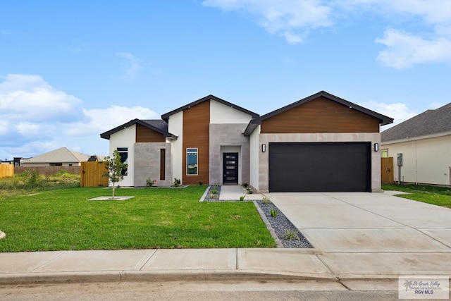 modern home with fence, an attached garage, stone siding, driveway, and a front yard